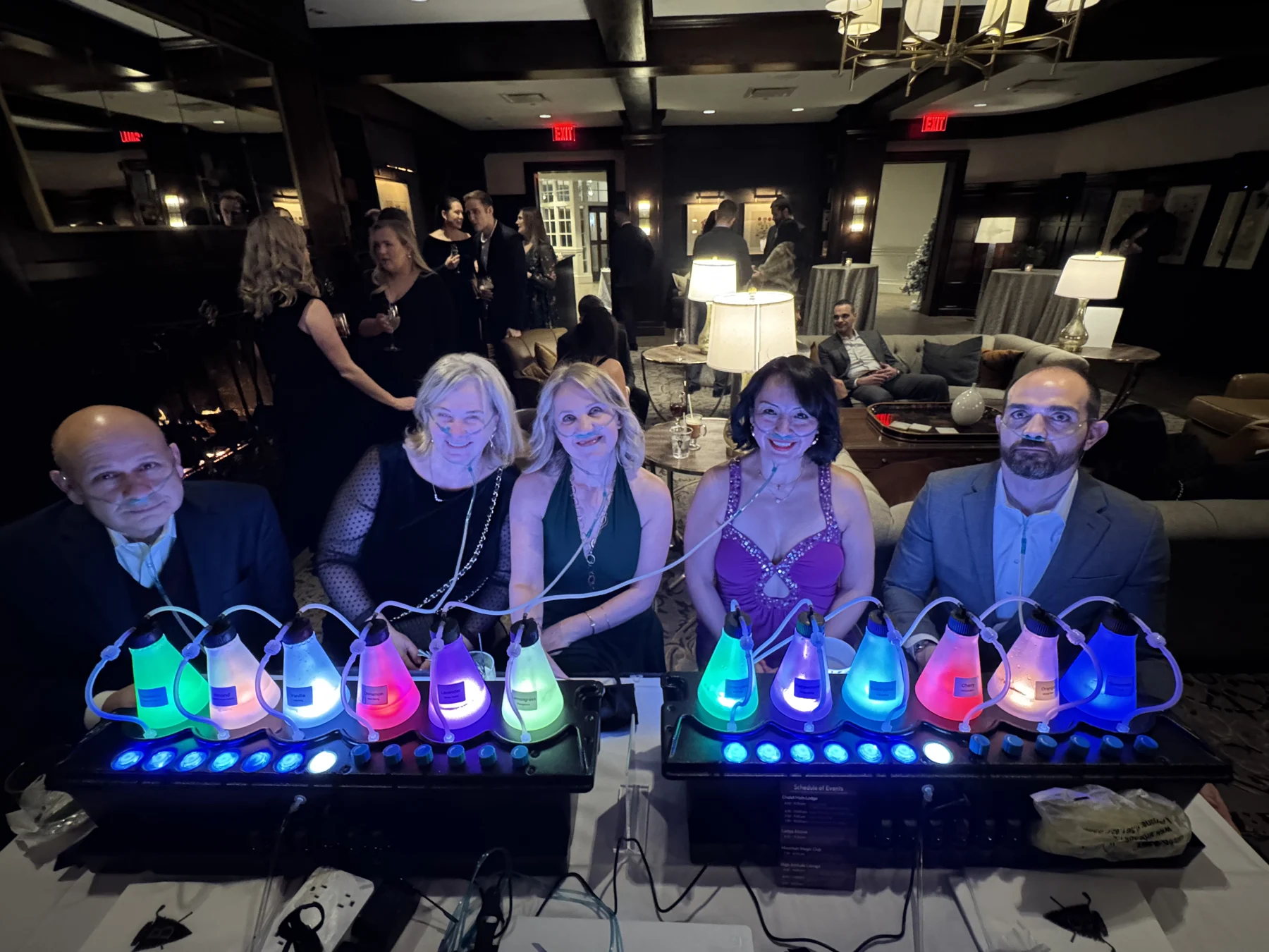 A group gathered around two illuminated stations in an event lounge