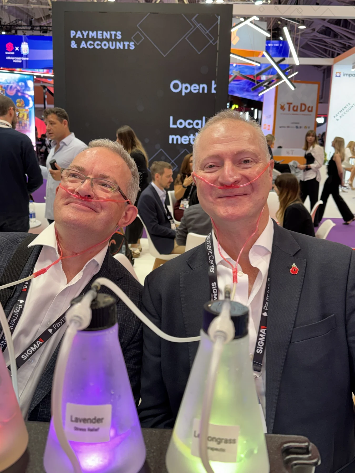Two smiling guests using the bar on a busy trade-show floor